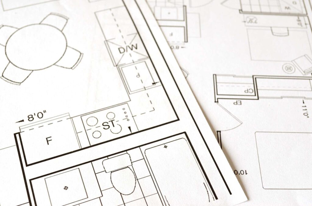 Image of a person holding a blueprint and standing in front of a construction site, representing the concept of building works and construction in the UK. The text "Understanding Permitted Development | A Guide to Building Without Planning Permission in the UK" is overlaid on the image