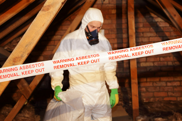 Professional inspecting a residential attic for the presence of asbestos-containing materials, promoting asbestos home safety for architectural website viewers.