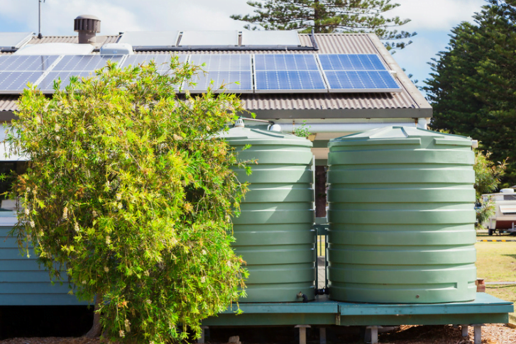 A UK home employing alternative rainwater harvesting methods, showcasing a rain chain and water butt, for sustainable water management in an architectural design